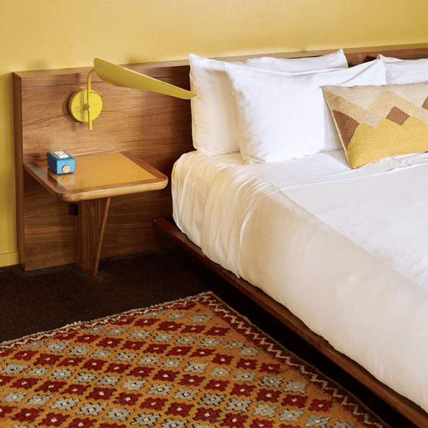 Bed with wooden headboard and attached yellow lamp